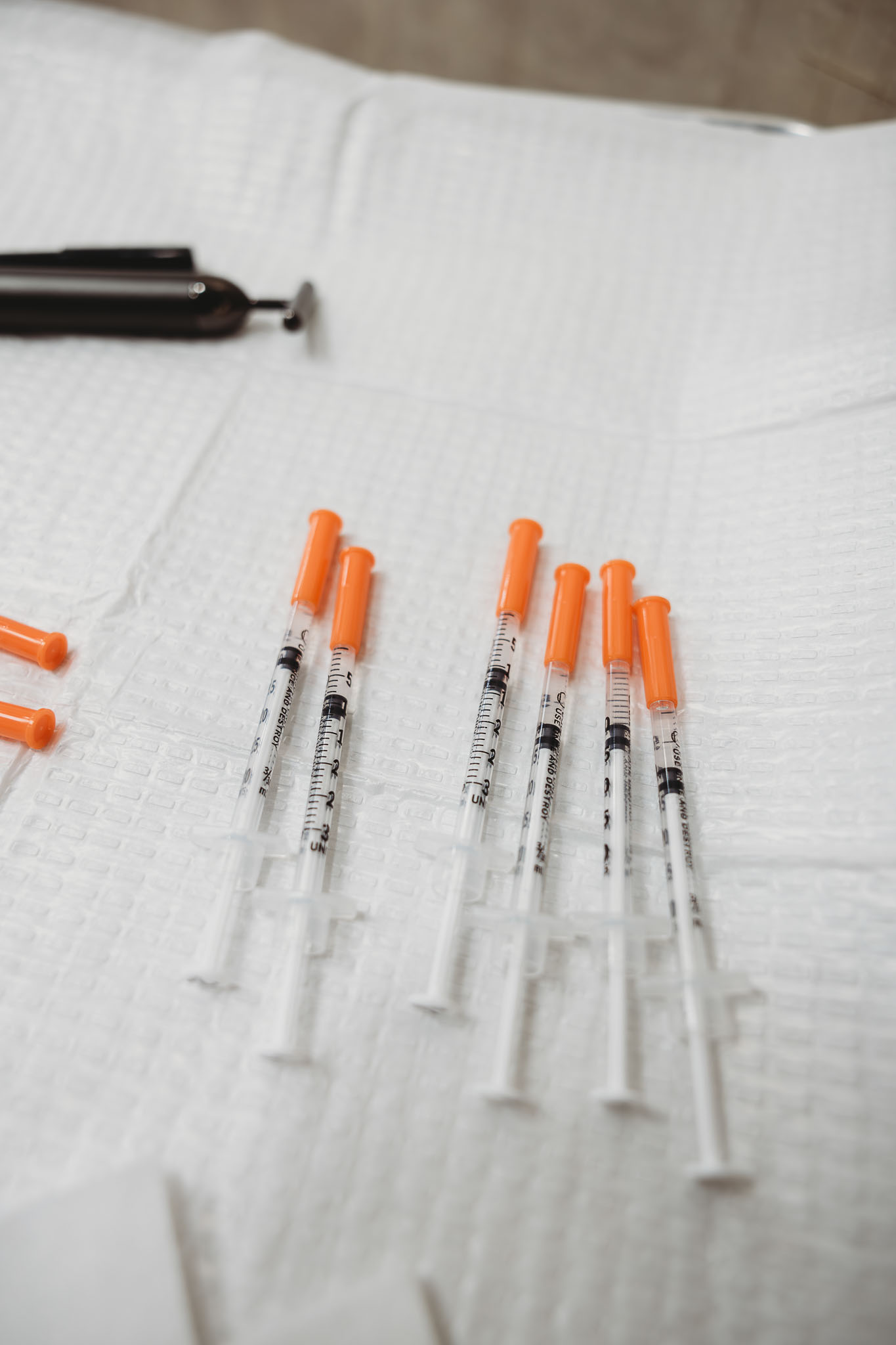 Multiple medical syringes or injectable treatment tools arranged neatly on a white surface.