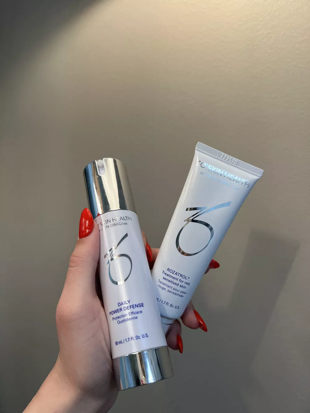 Woman's hand with red manicure holding ZO products